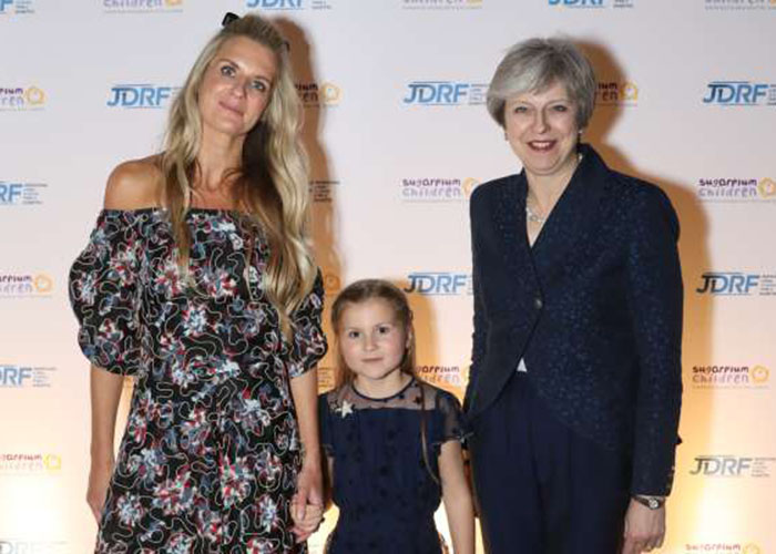 Jubie Wigan and her daughter stood smiling at the camera alongside former British Prime Minister Theresa May at Sugarplum fundraising ball for type 1 diabetes