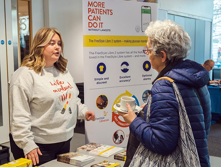 Lancets stand at a Discovery event with a representative from Lancets talking to a woman with type 1 diabetes about type 1 technology