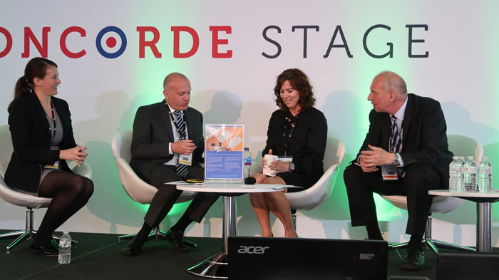 Rachel talking on stage whilst seated amongst a panel about the MDA card at the British-Irish Airports Expo at London Olympia