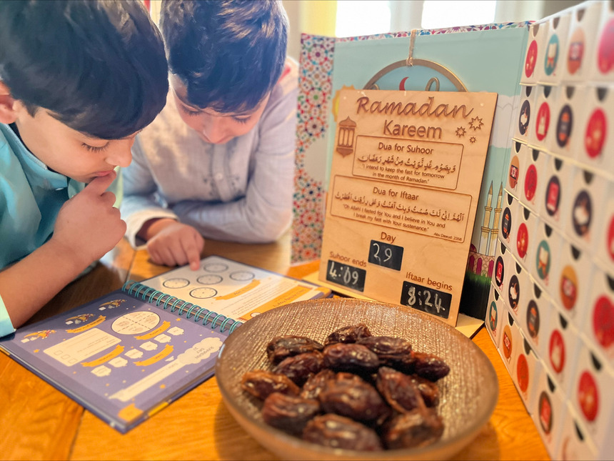 A photo of two boys reading a book and celebrating Ramadan