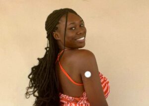 Temi Olonisakin smiling at the camera over her shoulder with her continuous glucose monitor visible.