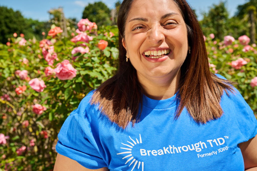 Smiling middle aged woman in front of pink rose bush in park