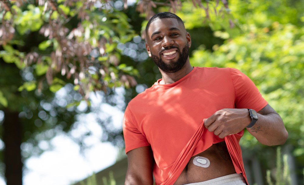 A man raising his t-shirt to show his continuous glucose monitor