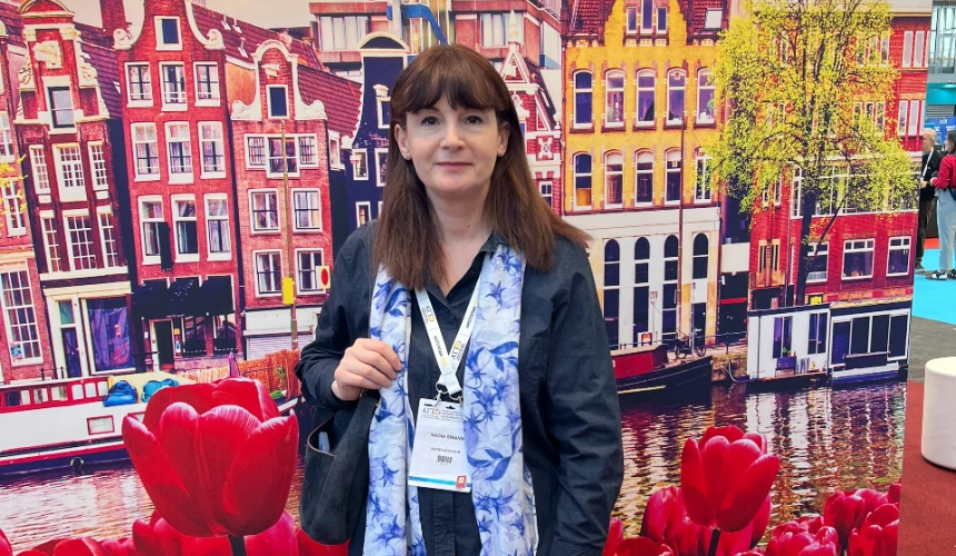 Nadia Swann standing in front of an illustrated back drop of Amsterdam at ATTD 2025