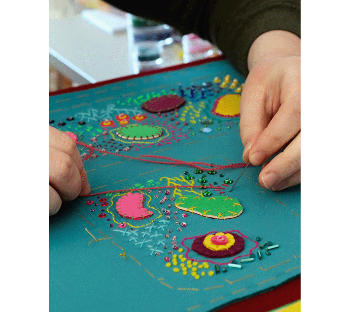 Megan Neville sewing stitches into her handbag using a needle and bold pink thread.