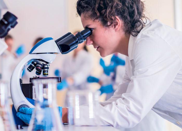 Scientist researcher woman in white coat using microscope in laboratory