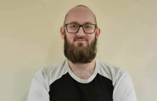 Researcher Dr Tom Wylie, a pale person with a beard and glasses.
