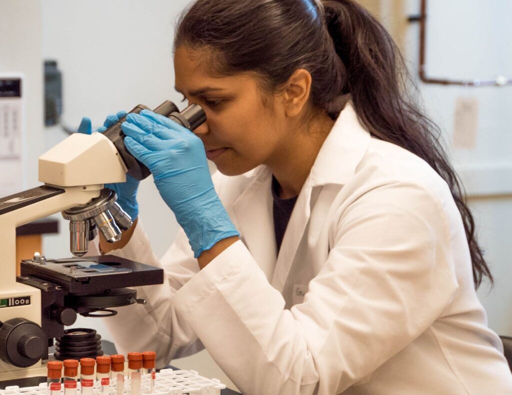 Female researcher looking into microscope