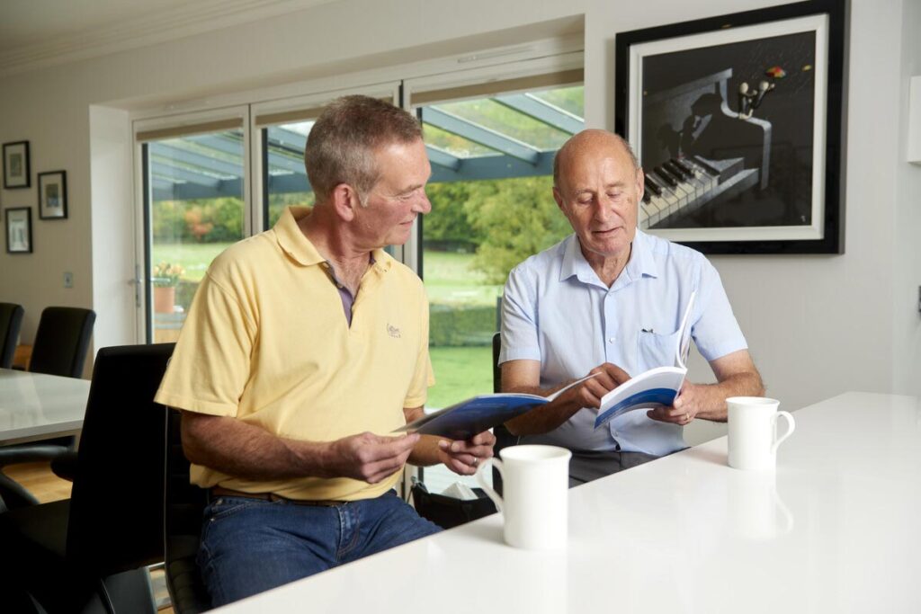Two older men at home reading type 1 diabetes information booklets.