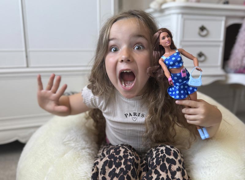 Excited girl holding Barbie with type 1 diabetes