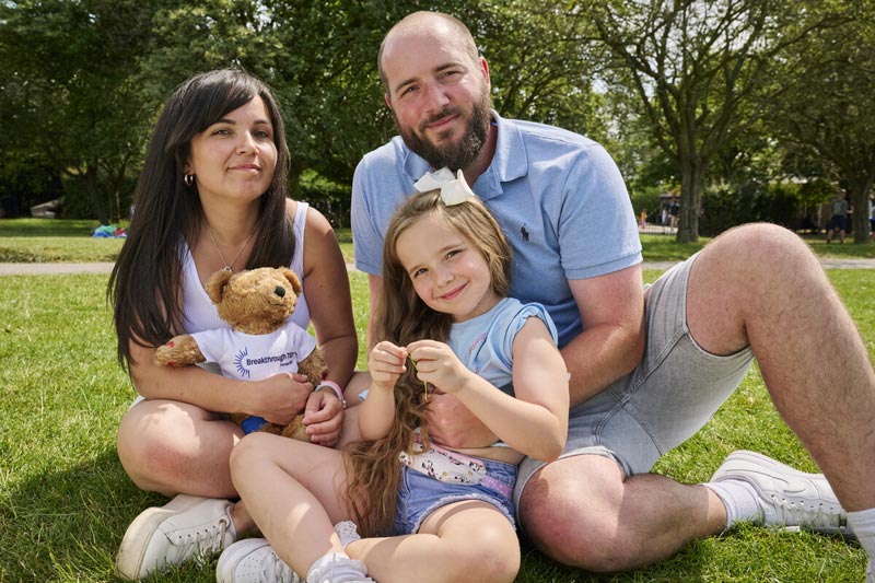 Smiling family sat in park with Rufus the Bear in Breakthrough T1D T-shirt