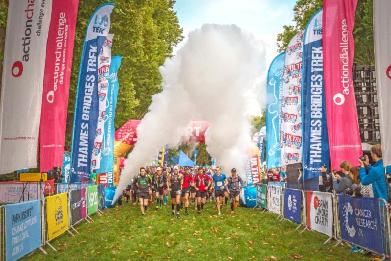Runners at the Ultra Challenge Thames Bridges Trek starting line with smoke rising