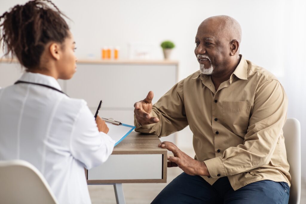 Older man speaking with female doctor whilst sat at a table