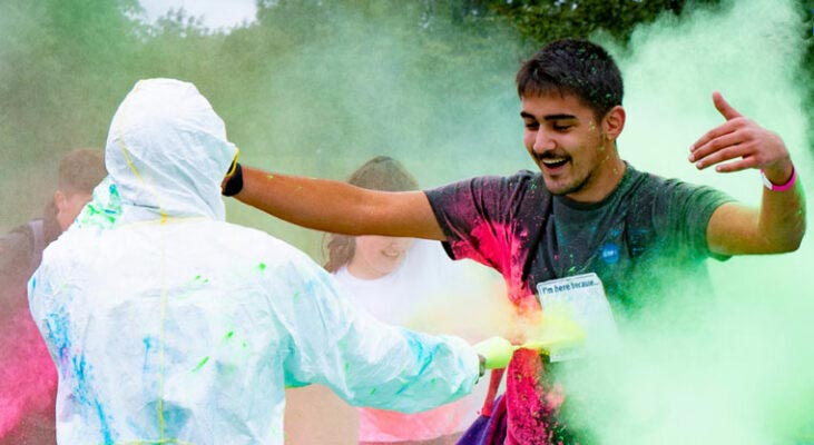 Young man being sprayed with colourful paint dust