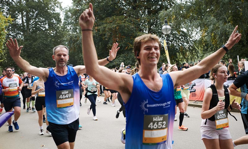 Two men in Breakthrough T1D vests running in a half marathon in a London park.