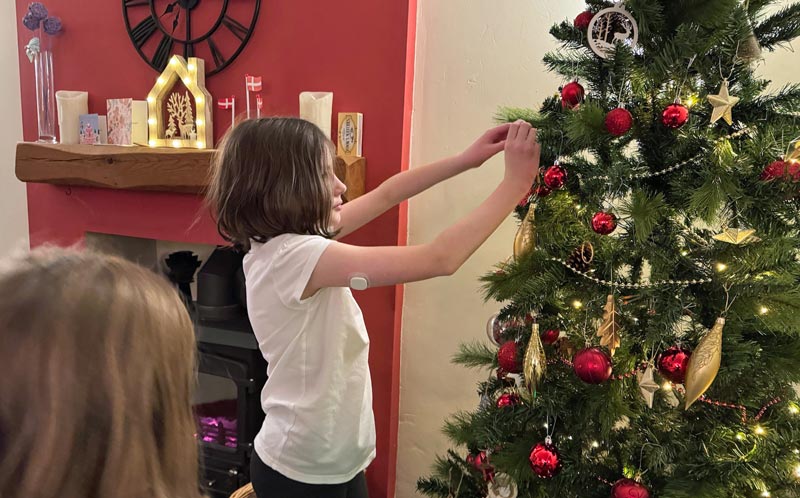 Bethany decorating a Christmas tree with CGM on arm