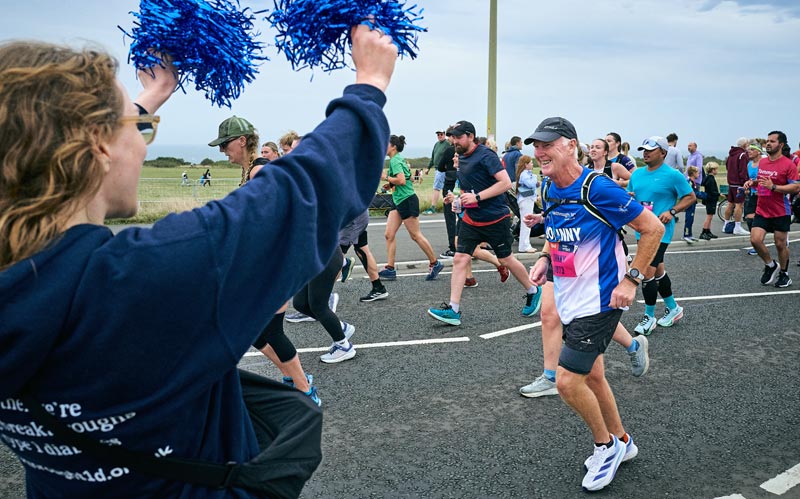 Johnny running in marathon with pom pom support raising money for type 1 diabetes