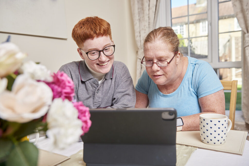 Two red headed women smiling and looking at a computer screen