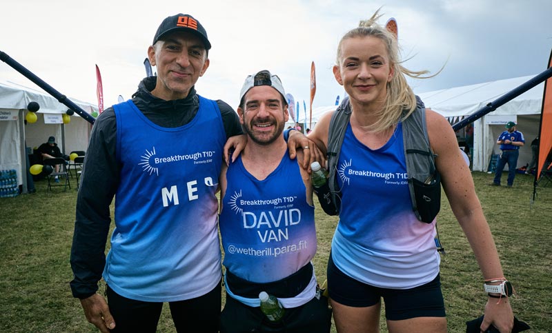 Three people posing by tent before running a marathon event to support people with type 1 diabetes