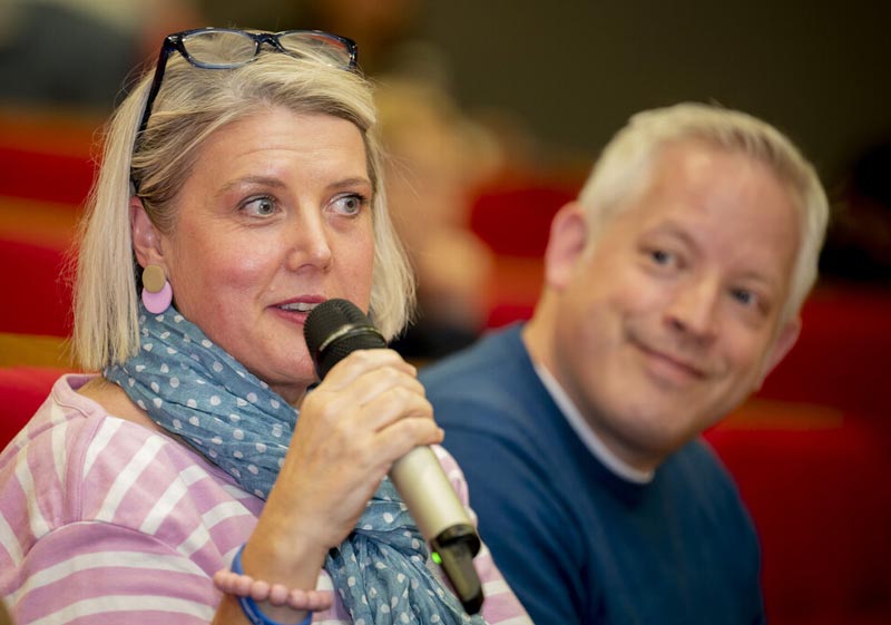 Woman at Discovery Day event in audience speaking into microphone