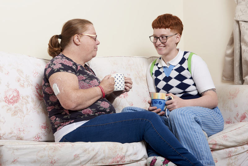 Two women on the sofa drinking tea or coffee.