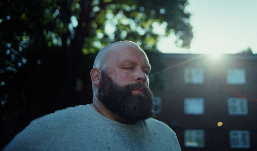 Bearded man stood outside closing his eyes.