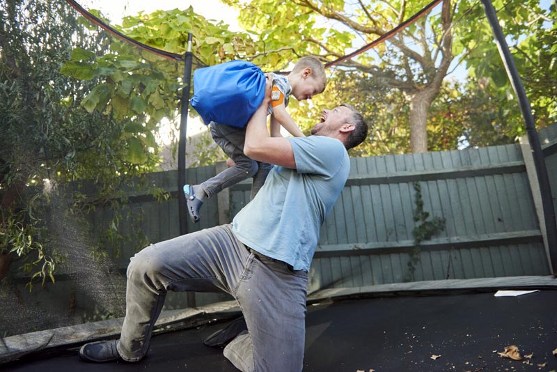 Father holding son in the air with visible CGM on arm