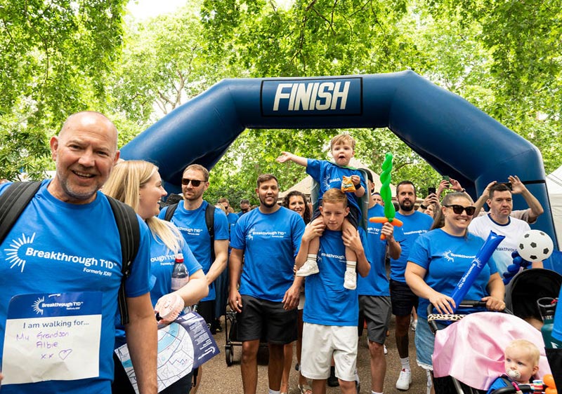 One Walk finish line with large group of family walkers in blue Breakthrough T1D T-shirts